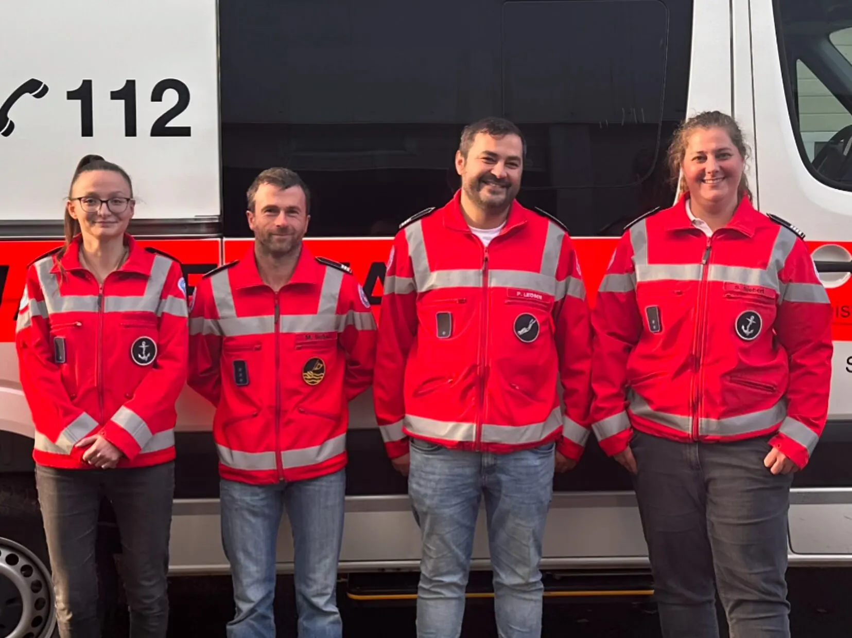 Die Ortsgruppenleitung der Wasserwacht Augsburg-Ost vor dem Einsatzfahrzeug