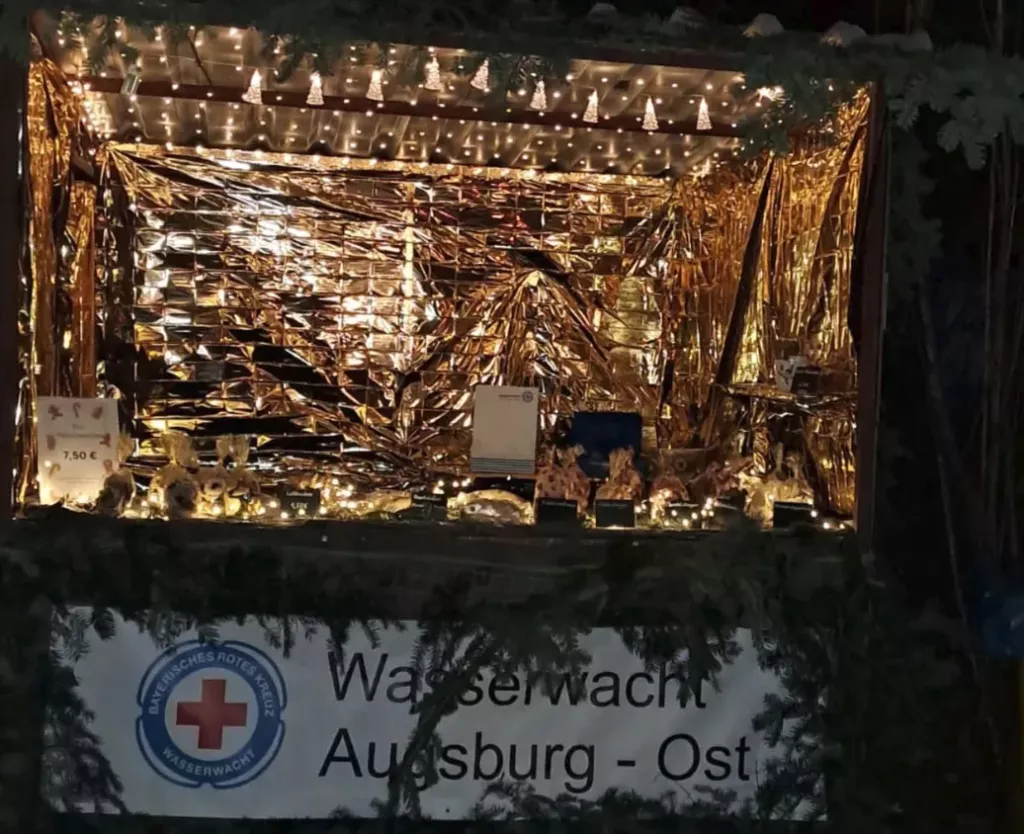 Weihnachtlich beleuchteter Stand der Wasserwacht Augsburg-Ost mit Plätzchen auf dem Weihnachtsmarkt in der Hammerschmiede